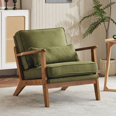 a green chair sitting on top of a white rug next to a table with a potted plant