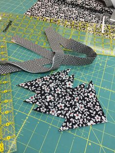 three pieces of black and white fabric sitting on top of a green cutting mat next to scissors