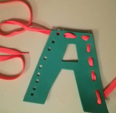 the letter a is made out of plastic and has pink dots on it, along with a pair of scissors