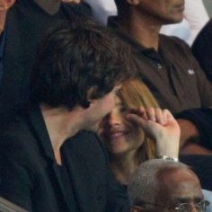 a man and woman sitting next to each other at a tennis game, with one holding her head in her hand