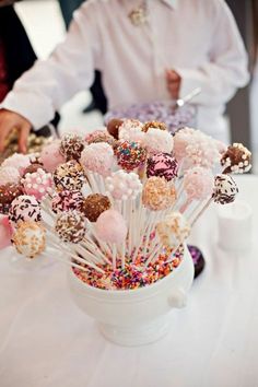 a white bowl filled with cake pops and sprinkles on top of a table