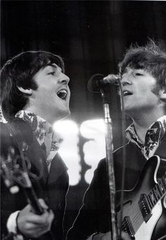 two young men singing into microphones while holding guitars