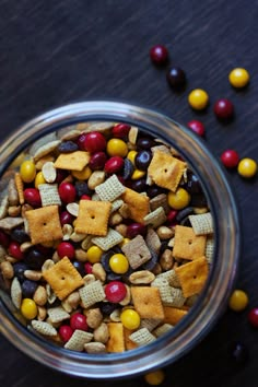 a glass bowl filled with candy corn and cheetos crackers on top of a wooden table