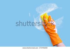 hand in orange rubber glove with yellow sponge on blue background