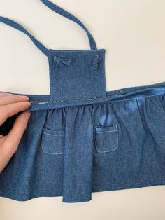 someone is sewing on the back of a pair of blue jean overalls that are being sewn together