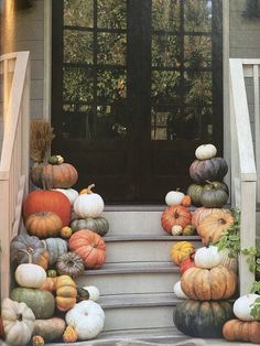 pumpkins and gourds on the steps of a house