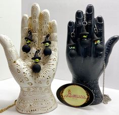 two black and white ceramic hand sculptures next to each other on a table with a gold chain hanging from it's wrist