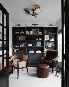 a home office with built in bookshelves and leather chairs