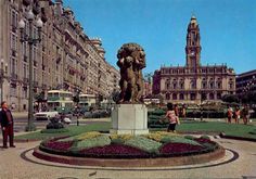 people are standing in the middle of a flower garden with a statue on it's base