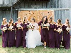 a bride and her bridal party standing in front of a barn door with their bouquets