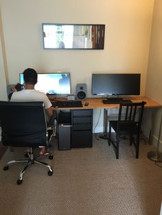 a man sitting at a desk with two computer monitors