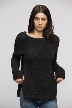 a woman wearing a black sweater with her hands on her hips and looking at the camera