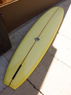 a yellow surfboard laying on the sidewalk