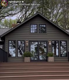 a house that has some plants on the front porch and stairs to it, with trees in the background