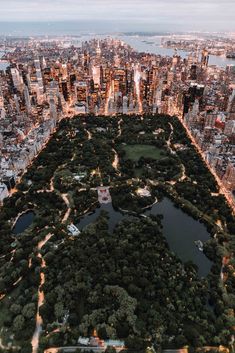 an aerial view of a city at night with lots of trees in the foreground