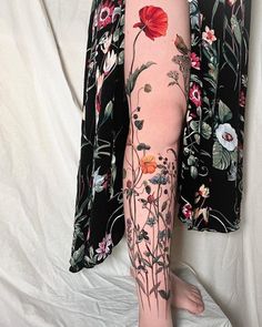 a woman's leg with flowers and leaves on it