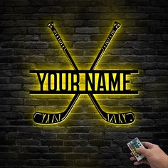 a person holding a remote control in front of a brick wall with the words your name on it