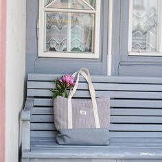 a gray and white bag sitting on top of a blue bench next to a window