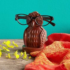 an owl figurine sitting on top of a wooden table next to yellow flowers