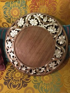 a decorative wooden plate sitting on top of a colorful couch