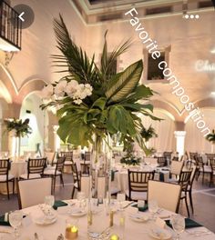 a table is set with plates, silverware and flowers in a tall glass vase