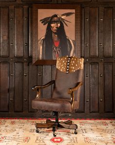 an office chair sitting in front of a wooden paneled wall with a painting on it