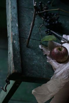 an apple sitting on top of a piece of paper next to some grapes and leaves