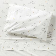 an unmade bed with white sheets and bunny print on the sheet set, along with two pillow cases