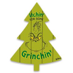 a green wooden christmas tree with the grinin for some sign in front of it