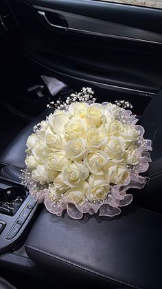 a bouquet of white roses sits in the center console of a car