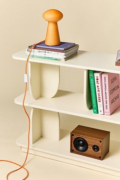 a white shelf with books and speakers on it