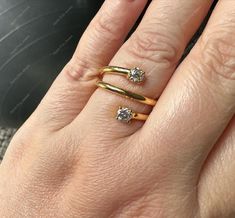 a woman's hand with two gold rings and one diamond ring on her finger