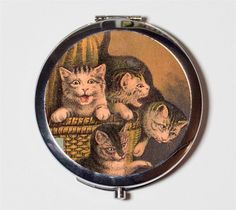 a compact mirror with kittens in a basket on the front, and an image of a cat behind it