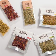 four bags of herb tea sitting on top of a white table next to each other