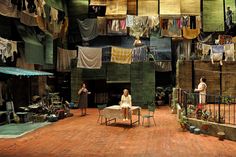 two women are sitting on chairs in the middle of a room with clothes hanging above them