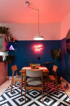 a dining room with a table and chairs in front of a neon sign on the wall