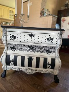 a white dresser with black and white designs on the drawers is sitting on a wooden floor