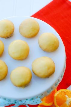 a white plate topped with yellow cookies on top of a red table cloth next to an orange