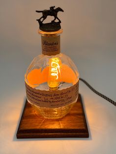 a glass bottle with an orange inside on a wooden base and a rope attached to it