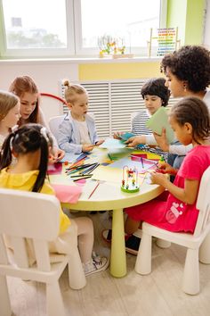 a group of children sitting around a table with crayons on it in front of them