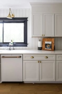 a kitchen with white cabinets and gold pulls on the handles, an open dishwasher