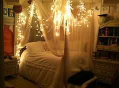 a canopy bed with lights hanging from the ceiling