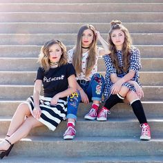 three young women sitting on steps with their legs crossed