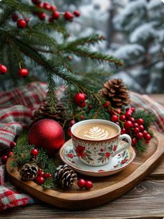 a cup of cappuccino sitting on top of a wooden tray next to christmas decorations