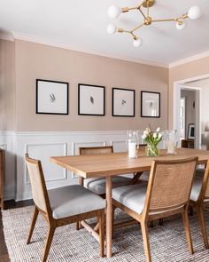 a dining room table with chairs and pictures on the wall