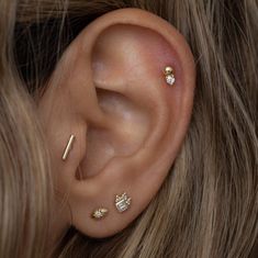 a close up of a person's ear with three piercings