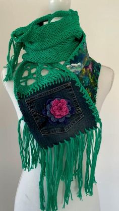 a mannequin wearing a green scarf with flowers and fringes on the sides