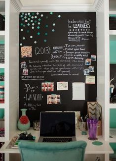 a desk with a laptop on it and a chalkboard in the corner behind it