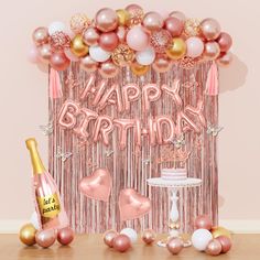 a happy birthday party with balloons, cake and champagne bottle in front of the backdrop