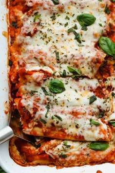 a casserole dish with meat, cheese and spinach leaves on the side